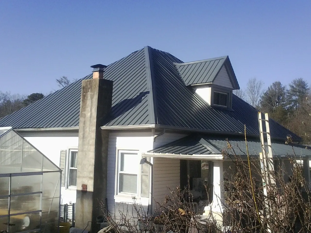 Dark blue standing seam metal roof on a white farmhouse with dormer — Slate & Tile Roof Repair by Roofing Brothers in Piru