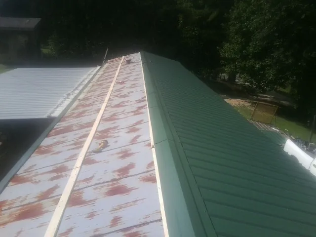 Old rusted panels beside newly installed green metal roofing — Wind Damage Roof Repair by Roofing Brothers in Piru