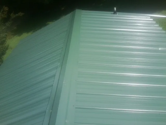 New green metal panels meeting at the ridge of a roof — Flat Roof Repair work by our crew in Piru