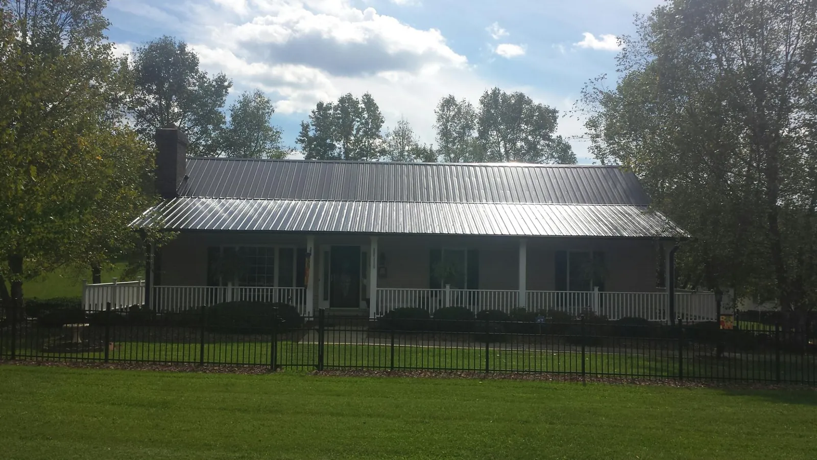 Gray metal roof on a brick ranch with a full width front porch — Gutter Guard Installation work by our crew in Piru