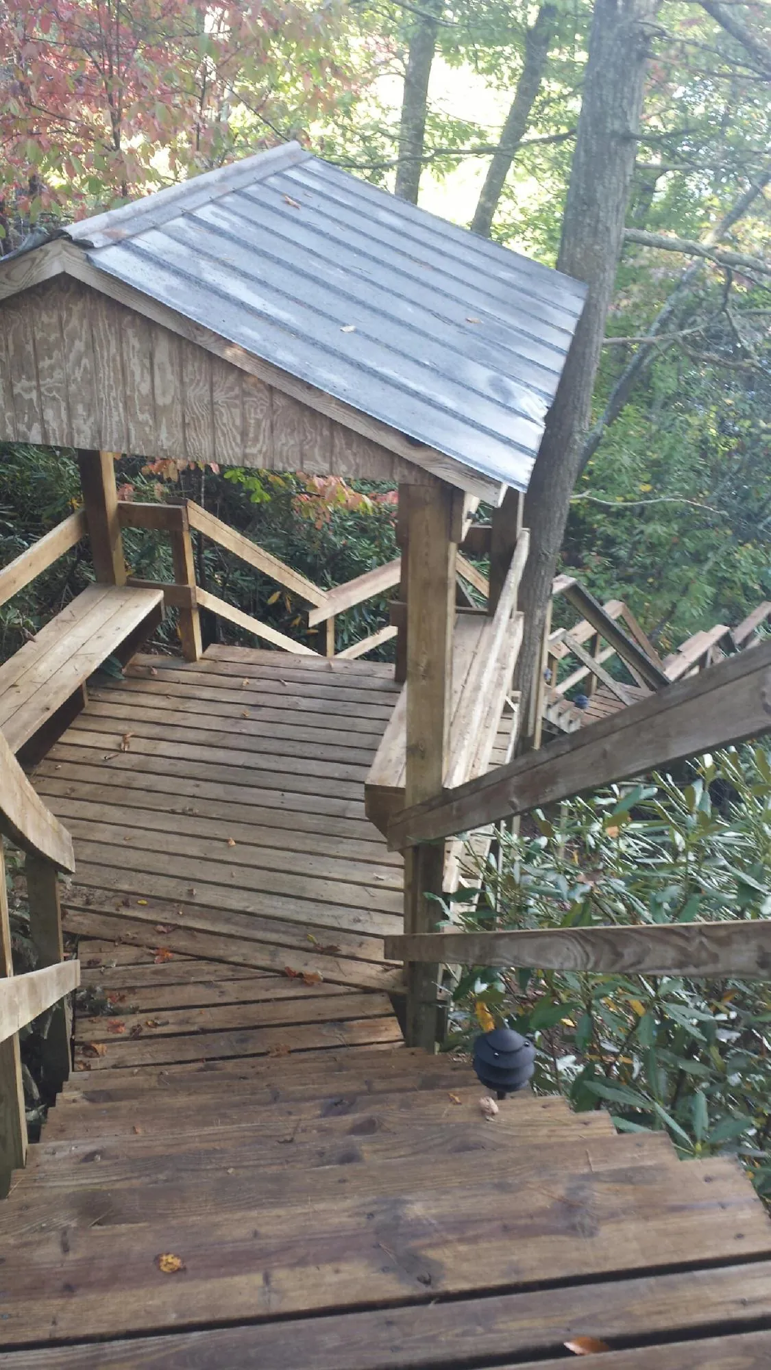 Metal roofed shelter over wooden steps on a wooded walkway — Skylight Repair & Installation work by our crew in Piru