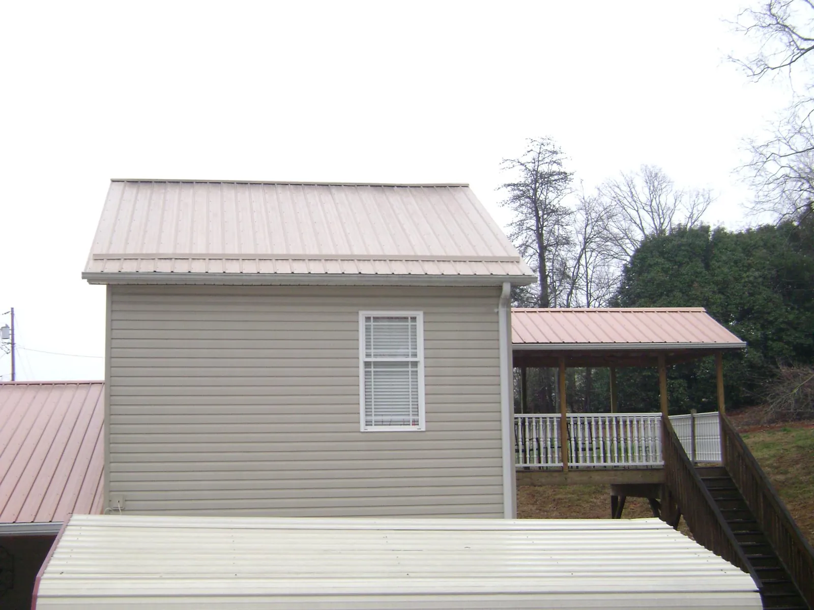 Tan metal roofs on a two story addition and attached porch, from a Roof Replacement job in Piru