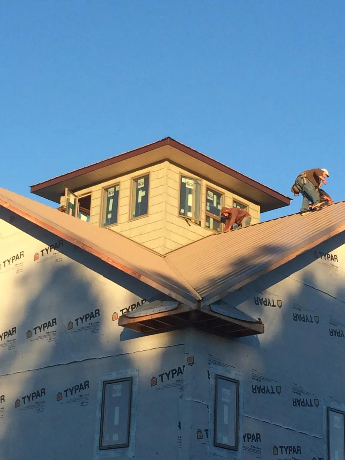 Roofers working around a rooftop cupola on a new metal roof at sunset — Roof Waterproofing in Piru by Roofing Brothers